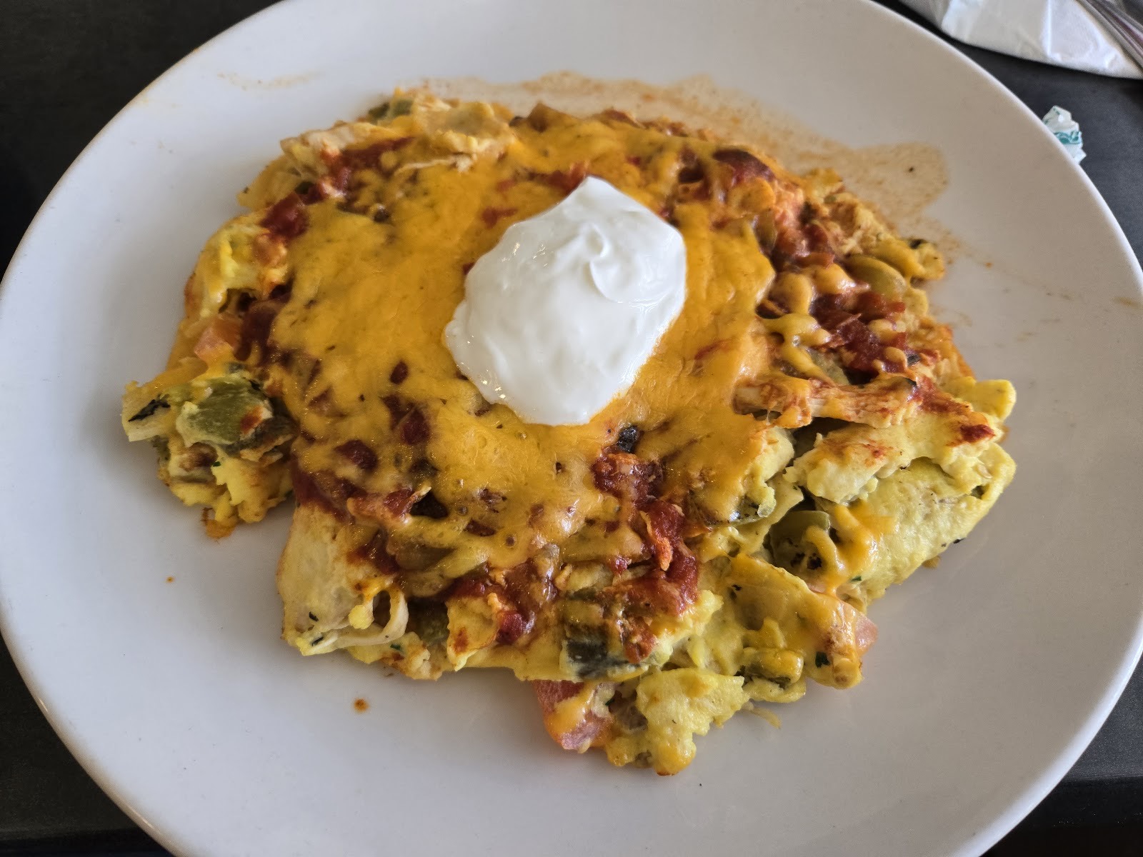 A scramble of eggs, chicken, green chiles and tomato under melted cheese, salsa and sour cream.